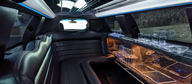 Sleek black limousine with chauffeur holding the door open.